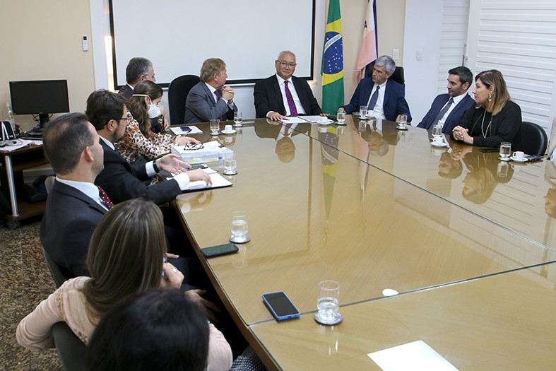 Foto mostra momento da reunião em sala do TJES, com participantes sentados em volta de uma comprida.