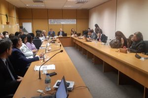 Foto em sala de reuniões com mesa em U e as pessoas participantes sentadas em volta da mesa.