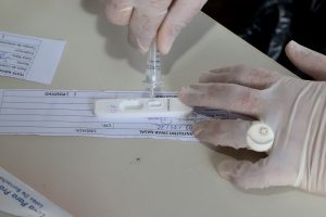 Foto mostra o detalhe de um teste de Covid-19 sendo feito pelas mãos de um enfermeiro.