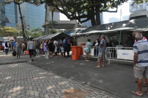 Foto mostra barracas montadas em uma praça para atendimento no 1º Mutirão PopRuaJud do Rio de Janeiro (RJ), com as pessoas em situação sendo atendidas dentro delas.