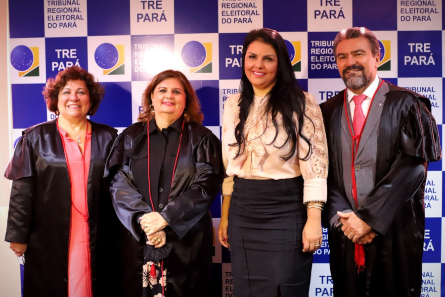 Foto mostra a ouvidora nacional, a presidente do TRE-PA, a ouvidora da Mulher do TRE-PA e o ouvidor do TRE-PA em pé, em frente a um painel com a logomarca do tribunal.