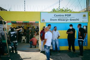 Foto mostra entrada do Centro Pop em Porto Velho com diversas pessoas conversando enquanto aguardam atendimento.
