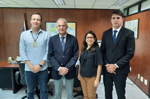 Foto mostra pessoas participantes da reunião em pé no gabinete do presidente do TRE-PE.