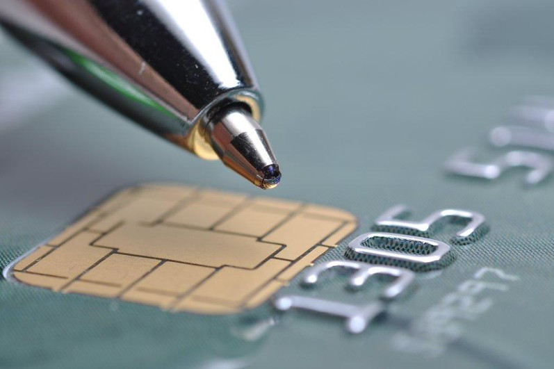 Foto mostra detalhes de uma caneta e um cartão de crédito com chip.