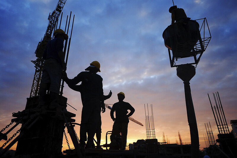 Foto mostra trabalhadores da construção civil em obra.