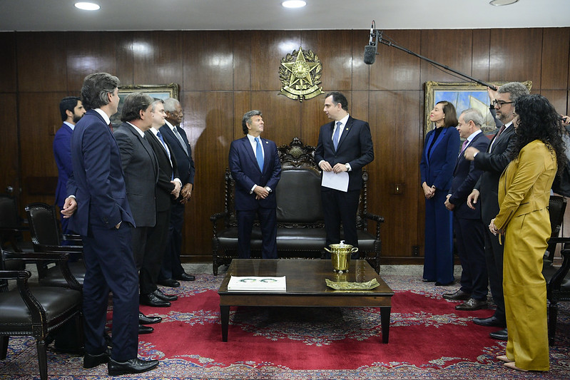 Foto mostra pessoas em pé no gabinete do presidente do Senado. Ao centro, o ministro Fux e o presidente do Senado se olham conversando sobre as propostas.