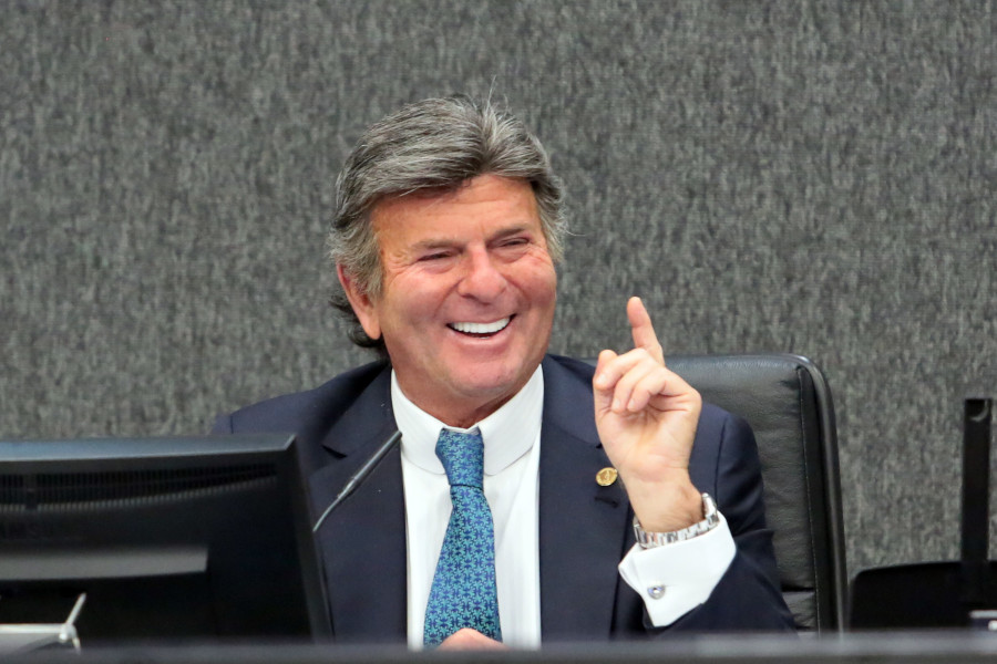 Foto mostra ministro Fux sentado em sua bancada no plenário do CNJ e sorrindo.