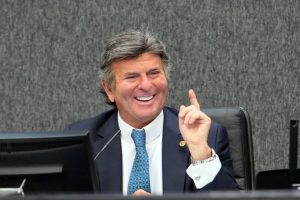 Foto mostra ministro Fux sentado em sua bancada no plenário do CNJ e sorrindo.