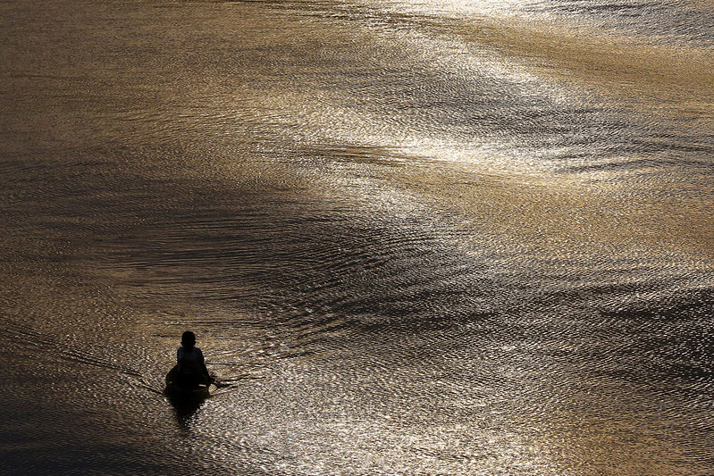 Foto mostra um menino em uma canoa dentro de um rio.