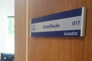 Imagem mostra porta com placa onde se lê as palavras Conciliação/Juizados no Tribunal de Justiça do Acre