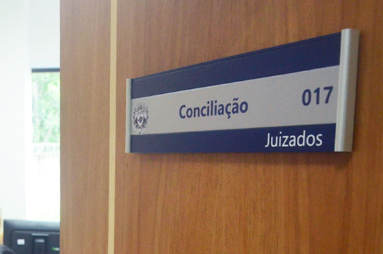 Imagem mostra porta com placa onde se lê as palavras Conciliação/Juizados no Tribunal de Justiça do Acre