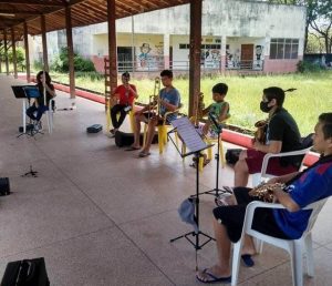 Imagem mostra crianças sentadas e tocando instrumentos musicais