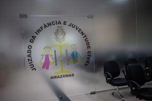 Imagem mostra porta de vidro com os dizeres "Juizado da Infância e Juventude Cível do Amazonas"
