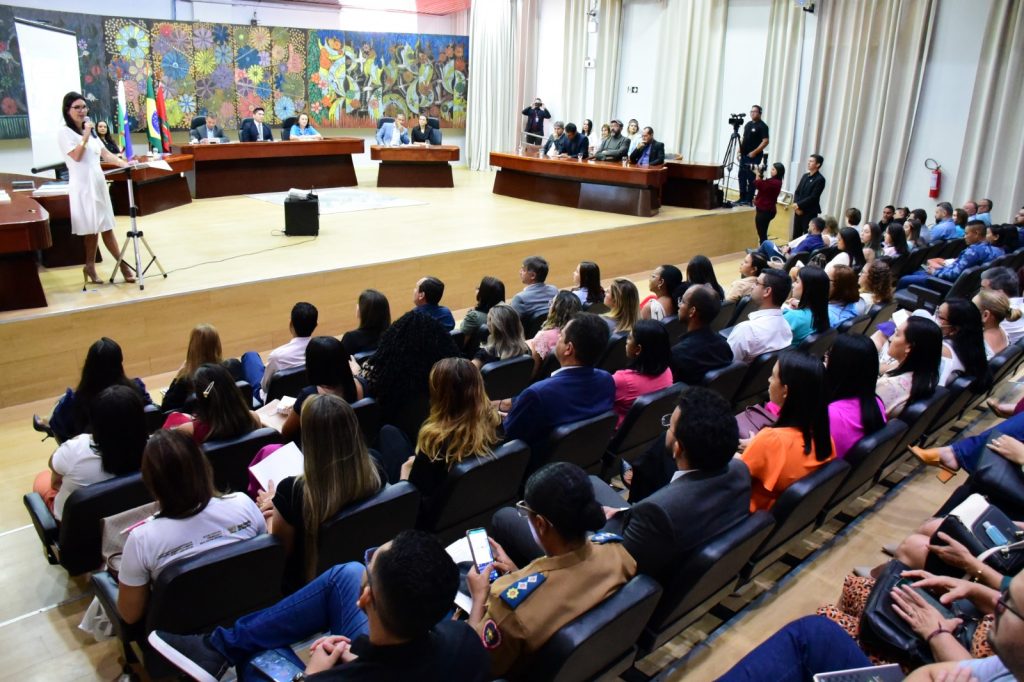 várias pessoas em um auditório e uma palestrante