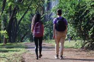 Jovens, com mochilas, caminham