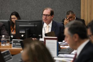 Fotografia em plano médio; Corregedor Nacional de Justiça, Ministro Luis Felipe Salomão, sentado sobre a mesa plenária, usando óculos de grau e vestido formalmente.