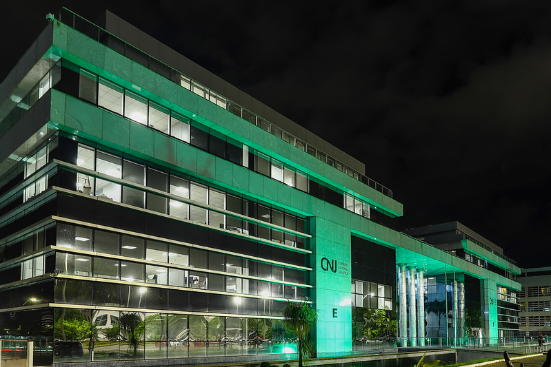 Fotografia da fachada do prédio do Conselho Nacional de Justiça. Estrutura iluminada com a cor verde, em alusão ao “Abril Verde” para a prevenção de trabalhos e doenças ocupacionais.