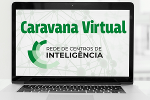 Um computador enquanto transmite uma imagem, que possui um fundo branco, com linhas e pontilhados que formam um globo. No centro e em destaque, a inscrição em verde “Caravana Virtual”, e em preto “Rede de Centros de Inteligência”. 