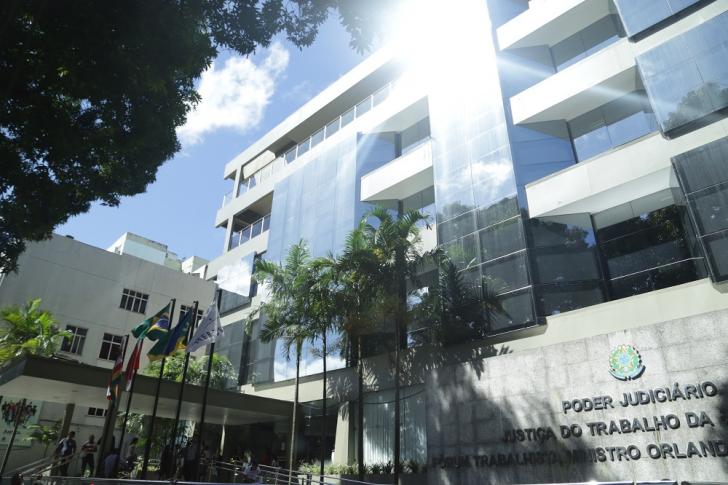 Fotografia da entrada do Fórum Trabalhista Ministro Orlando Teixeira da Costa. Há uma inscrição na entrada: “Poder Judiciário Justiça do Trabalho da 8ª região”. Com janelas de vidro, a entrada possui também várias palmeiras, além de outras árvores grandes. Há também alguns mastros com bandeiras.